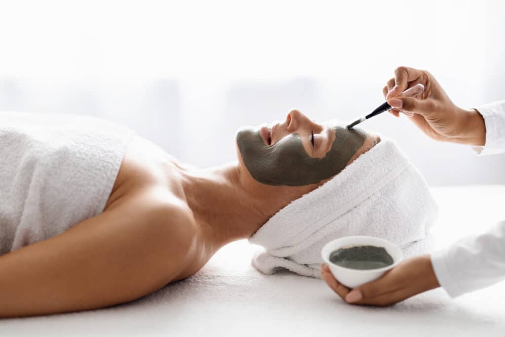 Cosmetologist making skincare beauty treatments to middle aged woman in spa salon
